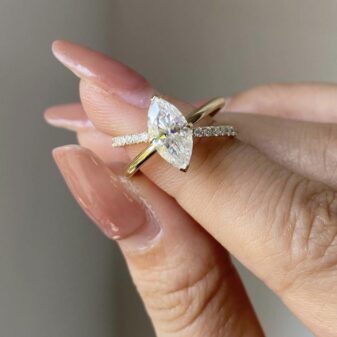 A modern twist on a classic, this unique engagement ring features a stunning marquise-cut diamond on a crossover pavé band.